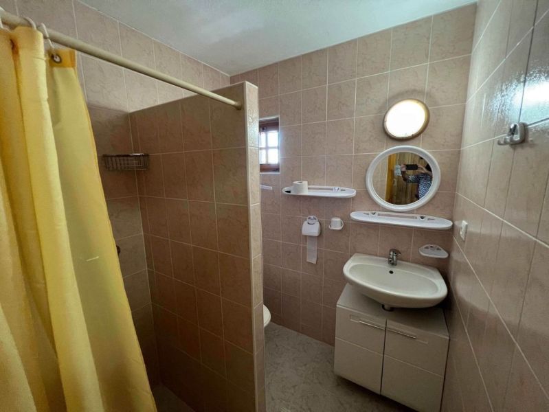 Bathroom in a family house with a sink, shower, and window.