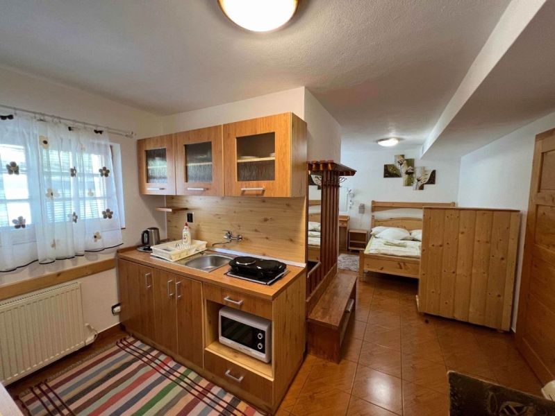 A kitchen in a family house with a kitchen unit and a bed, floor with wooden decor.