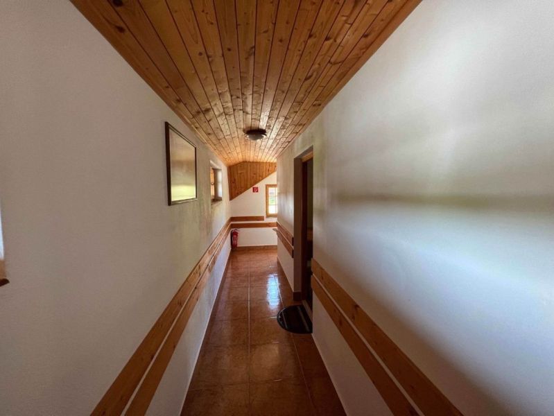 A hallway inside a family house with wooden paneling on the ceiling and walls.