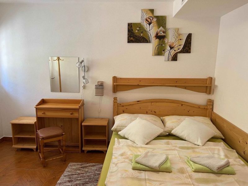 A bedroom in a family house with wooden furniture and a floral painting on the wall.