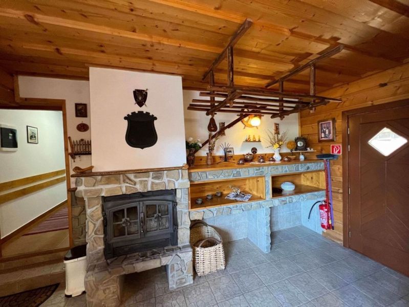 Interior of a family house with a tiled stove, wooden ceiling, and decorative shelves.