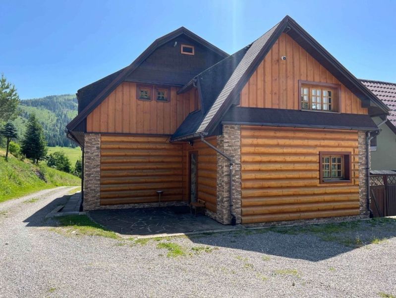A family house in Veľké Borové with a wood and stone-clad exterior near the forest.