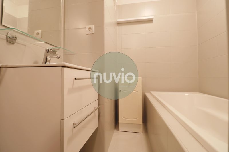 Bathroom in a 2-room apartment with a bathtub, white sink, and cabinet.