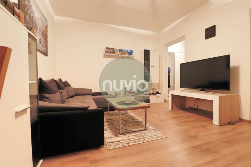 Living room in a two-room apartment with a wooden decor floor and a sofa.