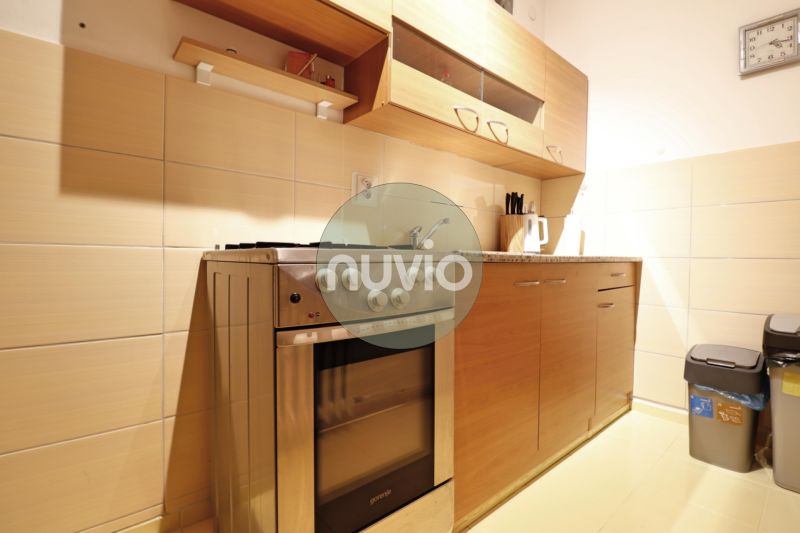 A kitchen in a 2-room apartment with a gas stove and wooden decor on the cabinets.
