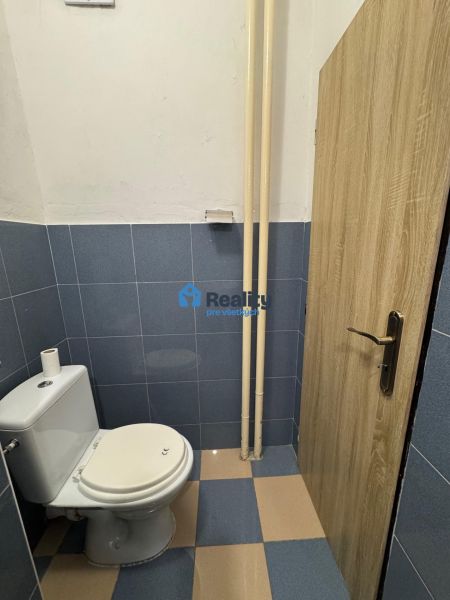 A toilet with blue tiles in a 2-room apartment, doors with a wooden decor.