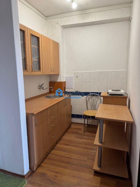 Compact kitchen in a 2-room apartment with light furniture and a wooden decor floor.
