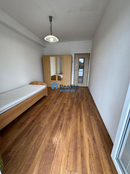 A room in a two-room apartment with a bed, a wardrobe, and a floor with a wooden decor.
