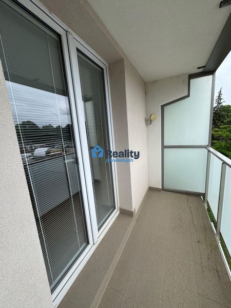 A balcony in a 2-room apartment with glass railings and a tiled floor.