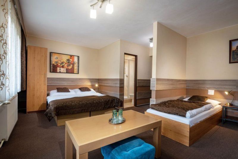 A room in a guesthouse with a double bed, a single bed, and a table.