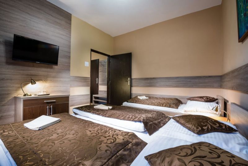 A room with a wooden floor decor, beds, and a television in a hotel and guesthouses.