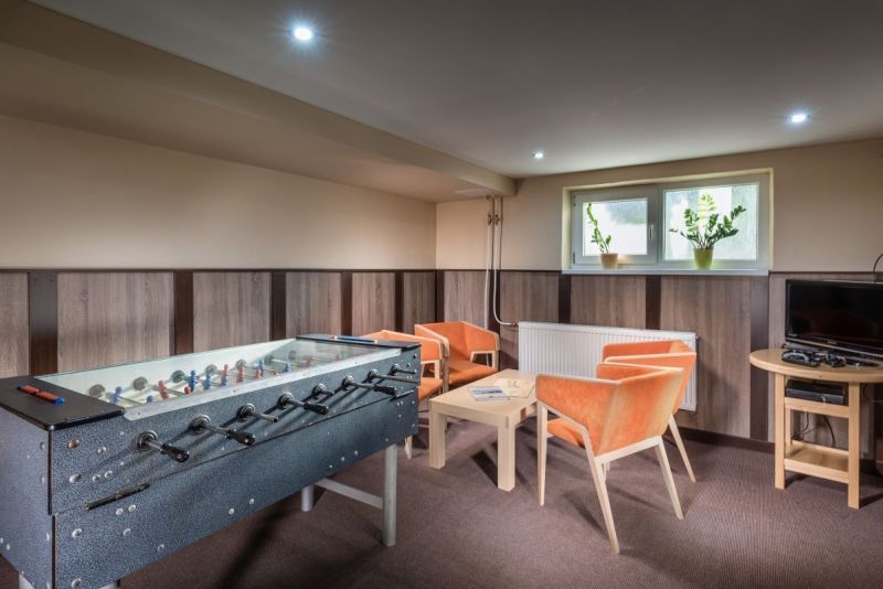 A relaxation room with a foosball table, orange armchairs, and a television in hotels and guesthouses.