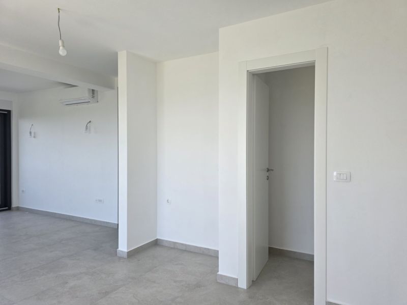 A white room in a 4-room apartment with air conditioning and ceramic flooring.