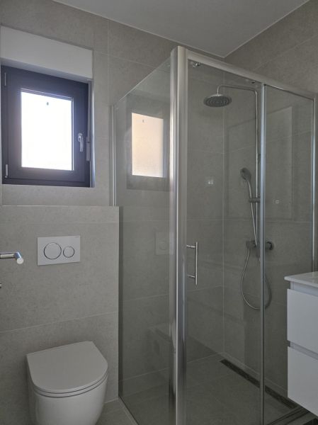 Bathroom with a glass shower enclosure and toilet in a 4-room apartment.