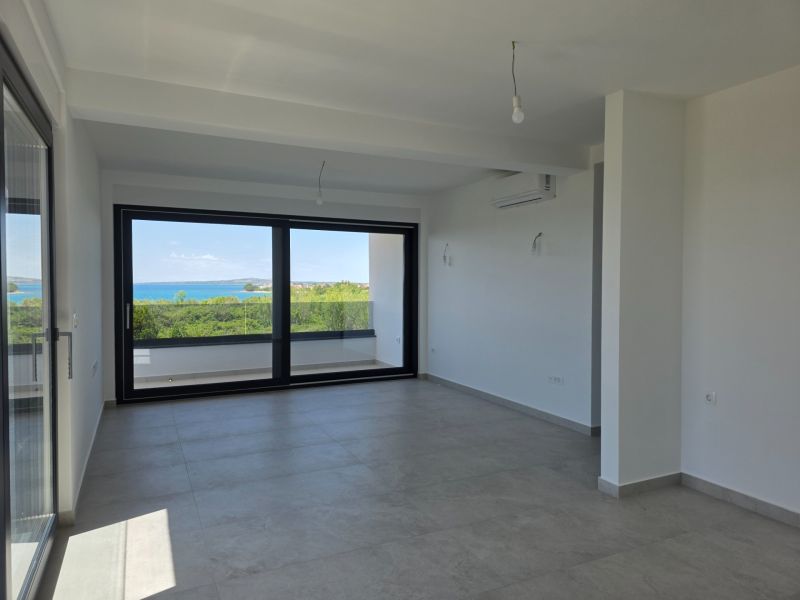 Living room in a four-room apartment with a large window and a view of the sea.