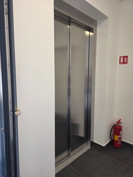 An elevator in a four-room apartment with tiles and a fire extinguisher.