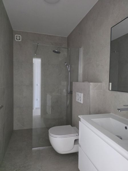 A bathroom with a shower, a sink, and a toilet in a 4-room apartment.
