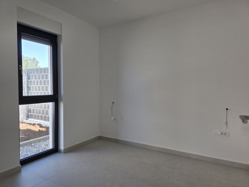 An empty room with a large window in a 4-room apartment, tiled floor.