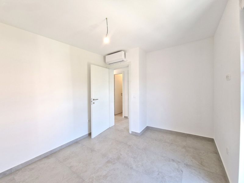 A neutrally furnished room in a 4-room apartment with air conditioning and ceramic flooring.