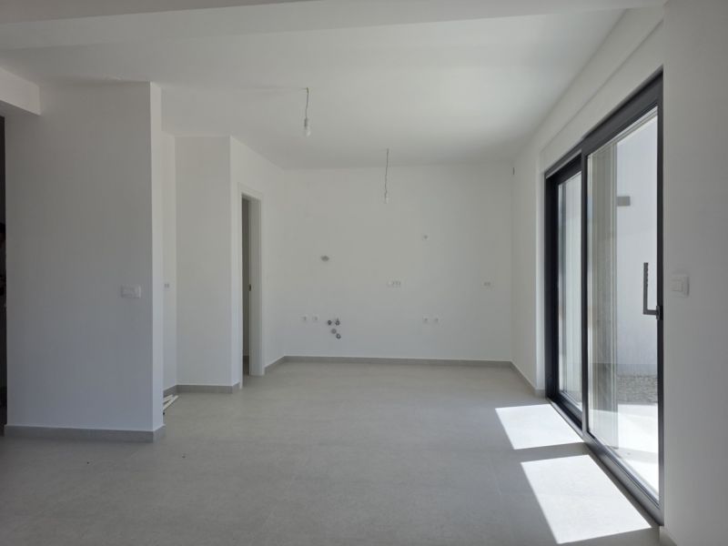 A spacious living area of a 4-room apartment with large windows and white walls.