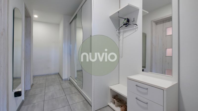 Hallway of a family house with tiles, white furniture, and a large mirror.