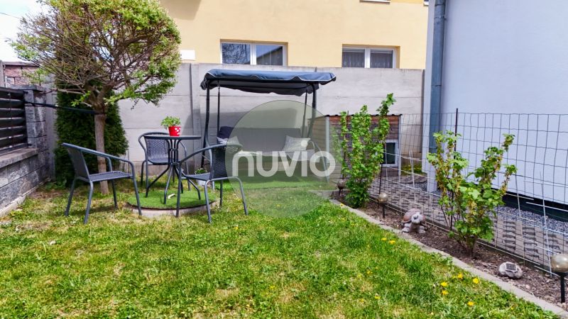 The garden of a family house in Košťany nad Turcom with a swing, chairs, and greenery.