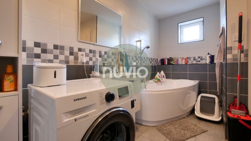 A bathroom in a family house with a corner bathtub and a Samsung washing machine.