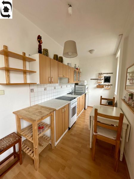 A kitchen in a studio apartment with a wooden decor floor and wooden furniture.