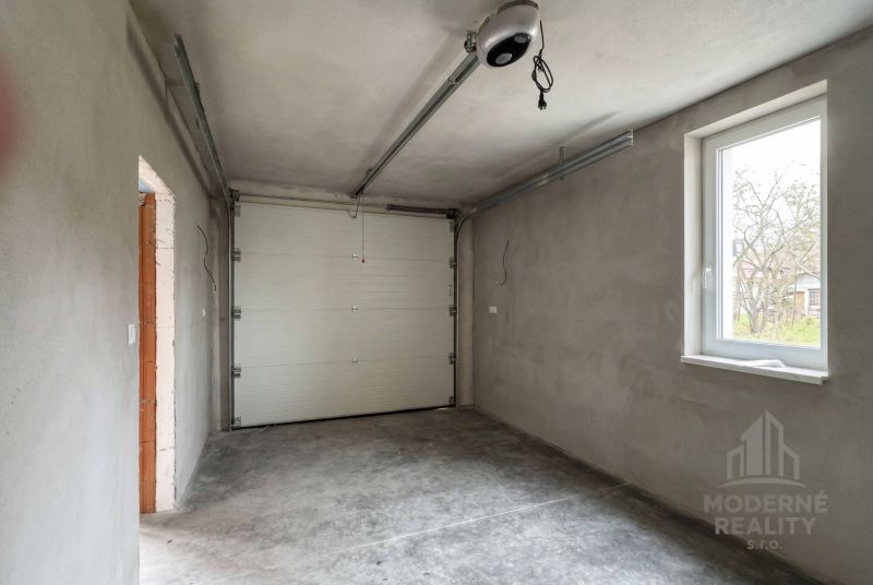 The interior of a garage in a family house with a concrete floor and a white garage door.