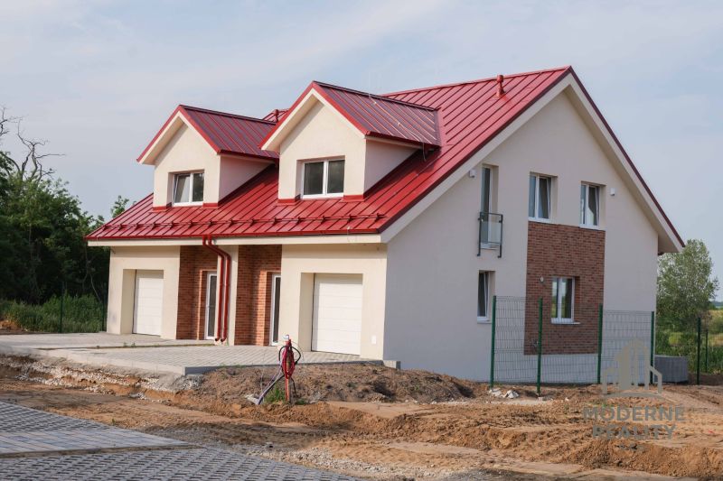 A family house in Andovce with a red roof and white garage doors.