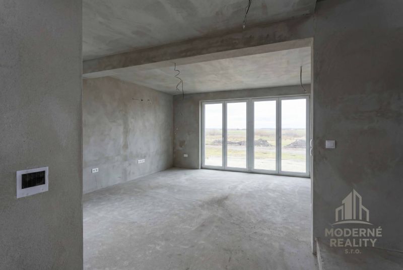 Interior of a family house with large glass doors and raw walls.