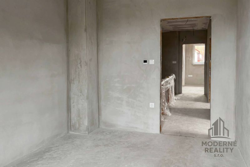 The interior of a family house with unfinished walls and a passage to another room.