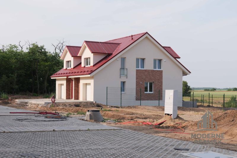 A family house in Andovce with a red roof surrounded by trees and a landscaped driveway.
