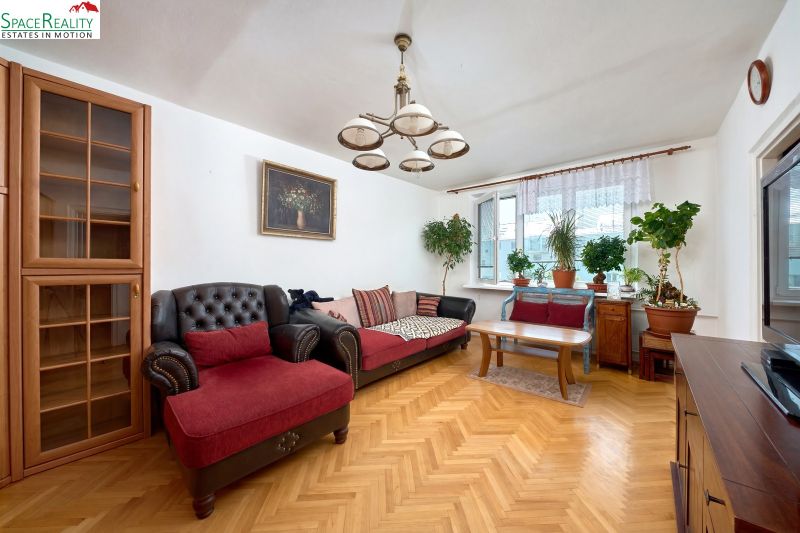 Living room in a two-room apartment with a wooden decor floor and comfortable seating.