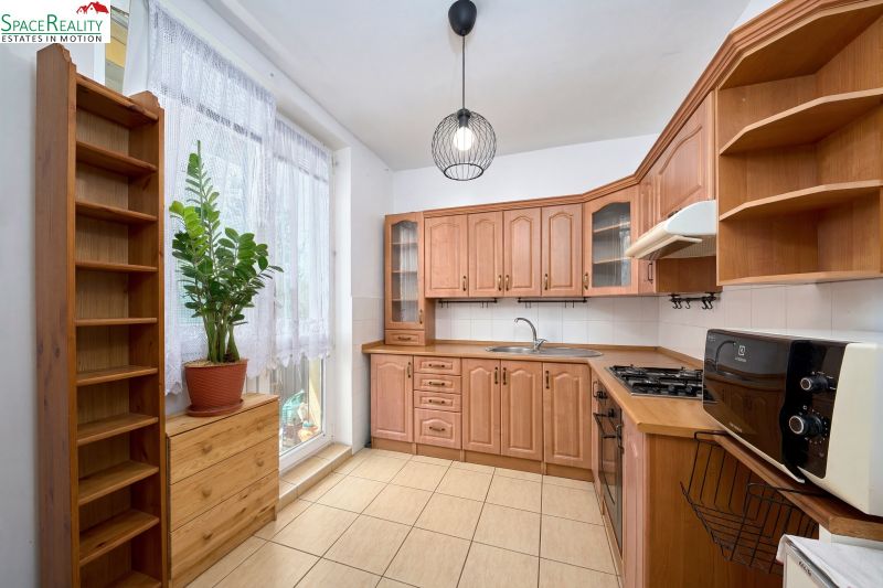 A kitchen in a 2-room apartment with a wooden decor kitchen unit and counter.