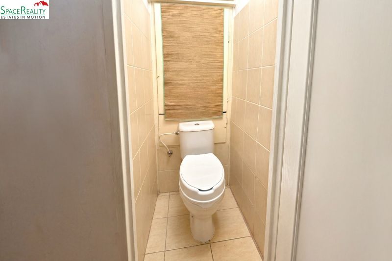 A toilet with light tiles in a 2-room apartment.