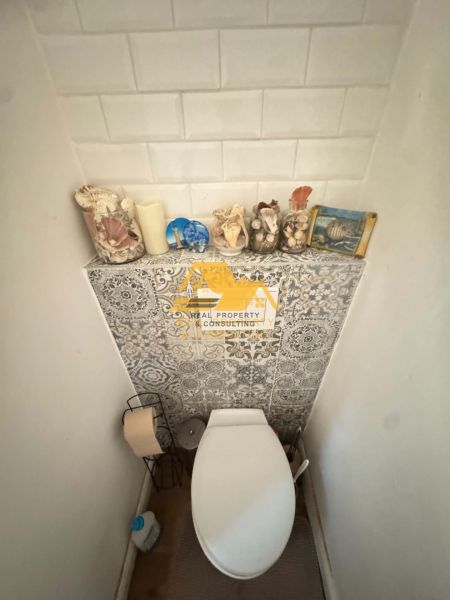A toilet with decorations and a wooden decor floor in a family house.