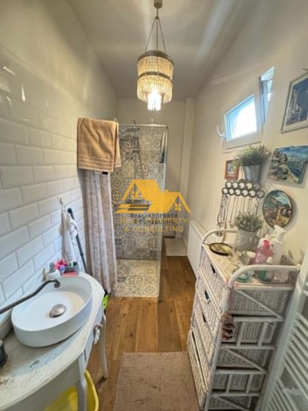 A bathroom with a wooden decor floor, a shower, and a sink, Family house.