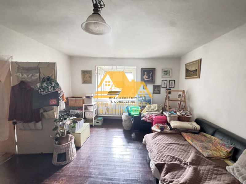 A room in a family house with a wooden decor floor, furnished with a sofa and decorations.
