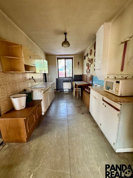 A kitchen in a family house with a long countertop, a dining table, and wall decorations.