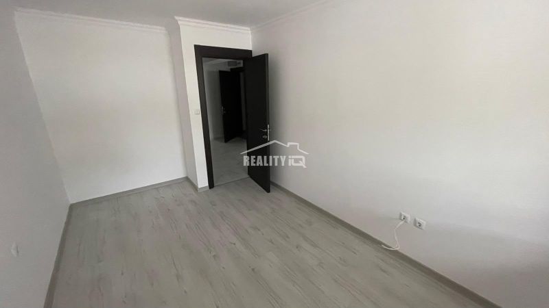 An empty room with a wooden floor and a door in a two-room apartment.