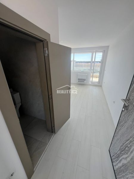The hallway in the 2-room apartment shows a floor with a wooden decor and a view of the terrace.