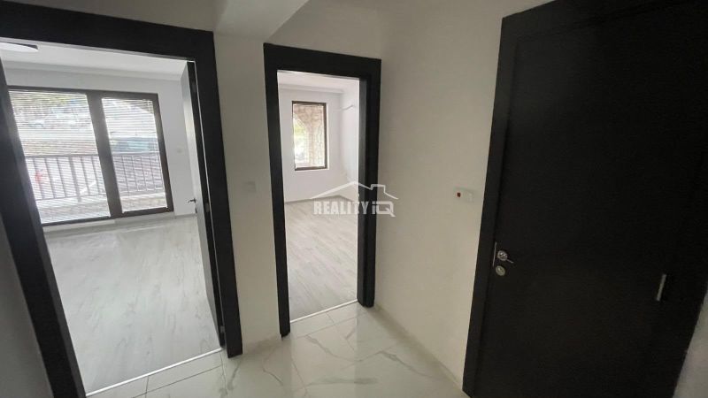 Interior of a 2-room apartment with light floors and dark doors.