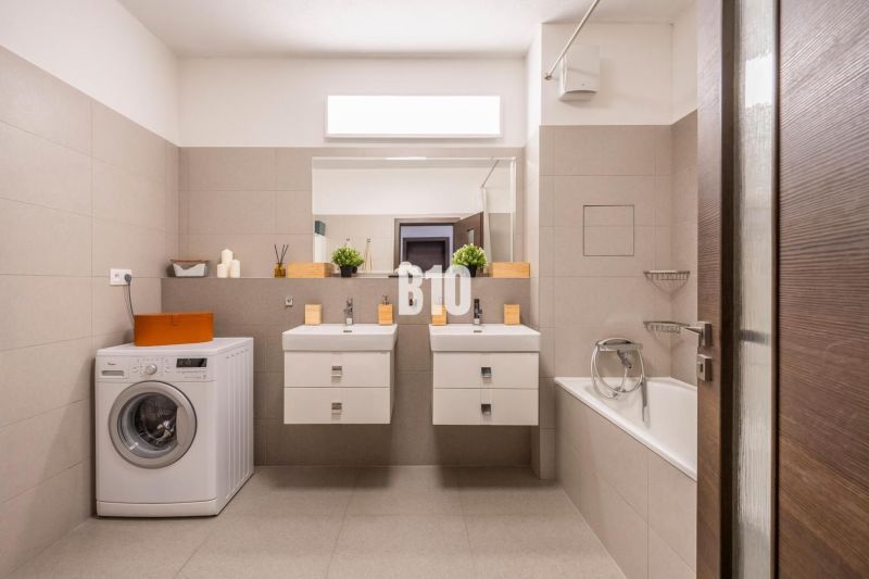 A bathroom in a 3-room apartment with two sinks and a washing machine.