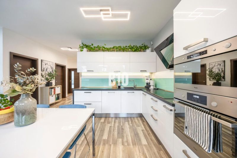 A kitchen with light furniture, modern appliances, and a floor with a wooden decor in a 3-room apartment.