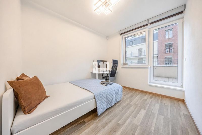 A room in a 3-room apartment with a bed, a desk, and a floor with a wooden decor.