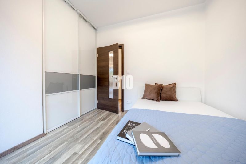 A bedroom in a 3-room apartment with a wood-patterned floor, a built-in wardrobe, and a bed with pillows.