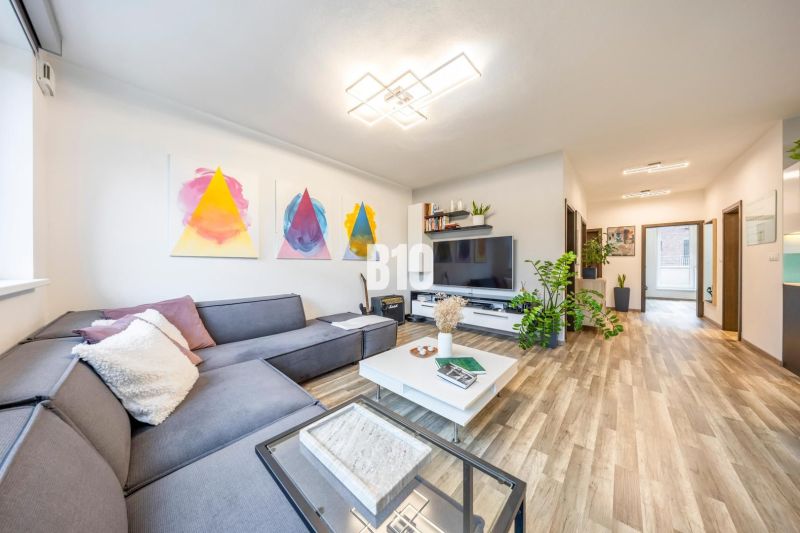 Living room in a 3-room apartment with a comfortable sofa, TV, and wooden decor flooring.