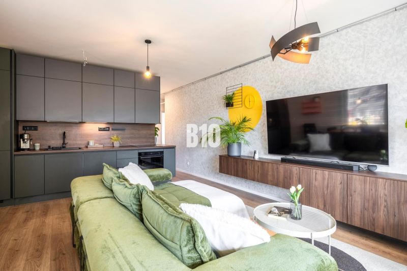 Living room with a kitchen in a 3-room apartment with a comfortable sofa and a floor with a wooden decor.