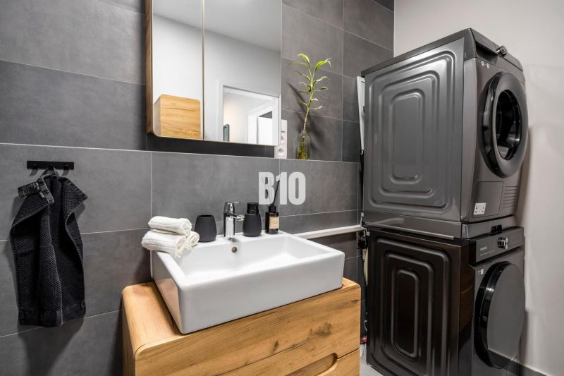 A bathroom in a 3-room apartment with a stylish sink, washing machine, and dryer.